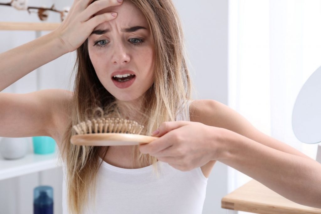 Women looking worried at her hair brush-Why Are You Losing Your Hair Buckhead Hair Restoration Savings